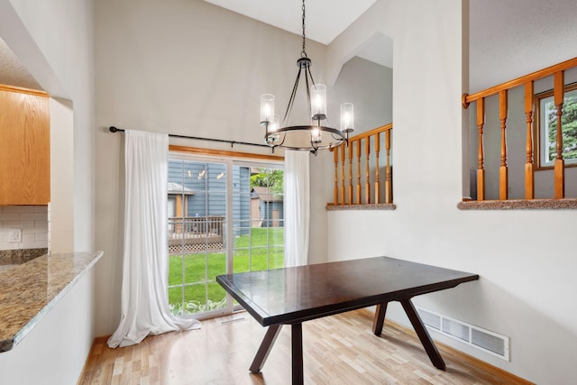 11813 Kerry St NW, Coon Rapids, MN 55433 - dining space featuring light wood-type flooring, healthy amount of natural light, a chandelier, and high vaulted ceiling