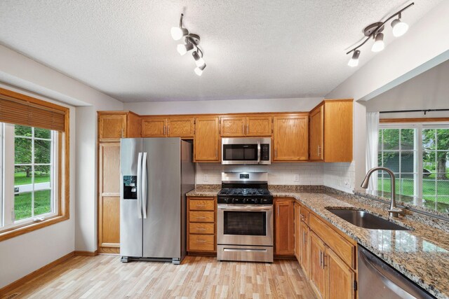 11813 Kerry St NW, Coon Rapids, MN 55433 - kitchen with appliances with stainless steel finishes, track lighting, light wood-style flooring, a textured ceiling, and brown cabinetry