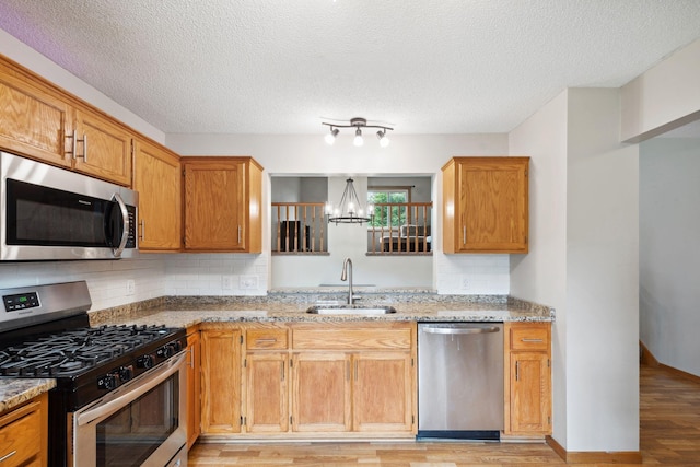 11813 Kerry St NW, Coon Rapids, MN 55433 - kitchen featuring stainless steel appliances, a chandelier, light wood-style flooring, light stone counters, and decorative backsplash