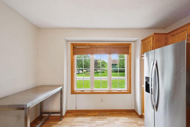 11813 Kerry St NW, Coon Rapids, MN 55433 - kitchen featuring stainless steel fridge, light wood-type flooring, brown cabinetry, and a textured ceiling