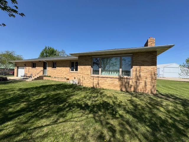 208 Mason Ave, Verndale, MN 56481 - rear view of house featuring a chimney, brick siding, an attached garage, and a yard