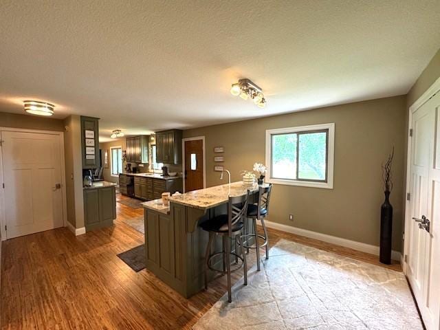 208 Mason Ave, Verndale, MN 56481 - kitchen featuring a breakfast bar, baseboards, light wood-type flooring, light stone counters, and a textured ceiling
