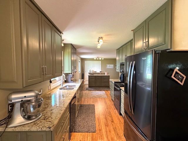 208 Mason Ave, Verndale, MN 56481 - kitchen with black appliances, light wood-style floors, a sink, green cabinetry, and light stone counters