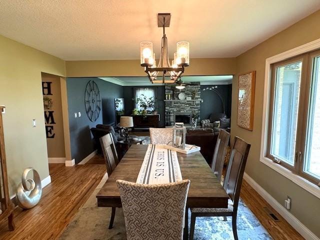 208 Mason Ave, Verndale, MN 56481 - dining room with a chandelier, wood finished floors, baseboards, and a stone fireplace