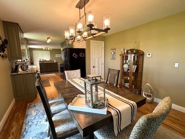 208 Mason Ave, Verndale, MN 56481 - dining room with light wood-style flooring, a chandelier, and baseboards