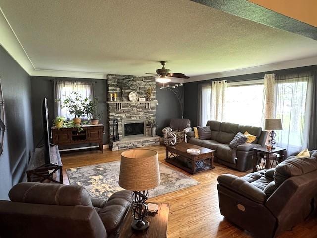208 Mason Ave, Verndale, MN 56481 - living area with a ceiling fan, a textured ceiling, a stone fireplace, and wood finished floors