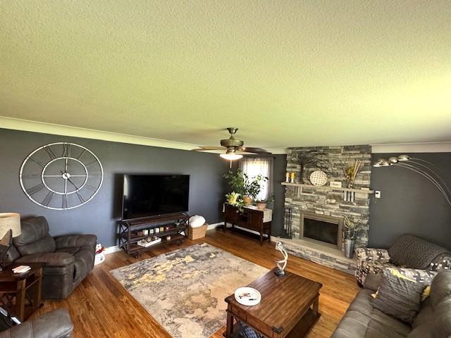 208 Mason Ave, Verndale, MN 56481 - living area with a textured ceiling, wood finished floors, a fireplace, ornamental molding, and ceiling fan
