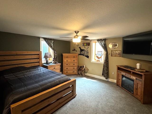 208 Mason Ave, Verndale, MN 56481 - bedroom with a textured ceiling, carpet flooring, baseboards, a fireplace, and ceiling fan
