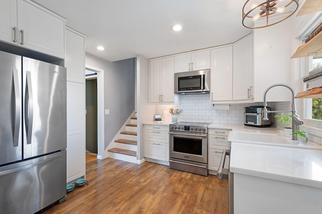 3646 Buchanan St NE, Minneapolis, MN 55418 - kitchen featuring stainless steel appliances, tasteful backsplash, white cabinets, baseboards, and wood finished floors