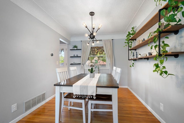 3646 Buchanan St NE, Minneapolis, MN 55418 - dining room featuring a chandelier, wood finished floors, baseboards, and a textured ceiling