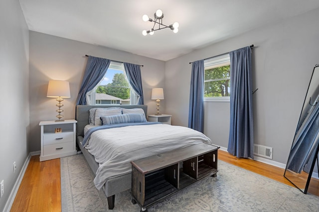 3646 Buchanan St NE, Minneapolis, MN 55418 - bedroom with multiple windows, a chandelier, light wood-style flooring, and baseboards