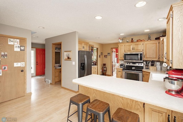 1727 33rd St S, Moorhead, MN 56560 - kitchen with appliances with stainless steel finishes, light brown cabinetry, a peninsula, light countertops, and light wood-style floors