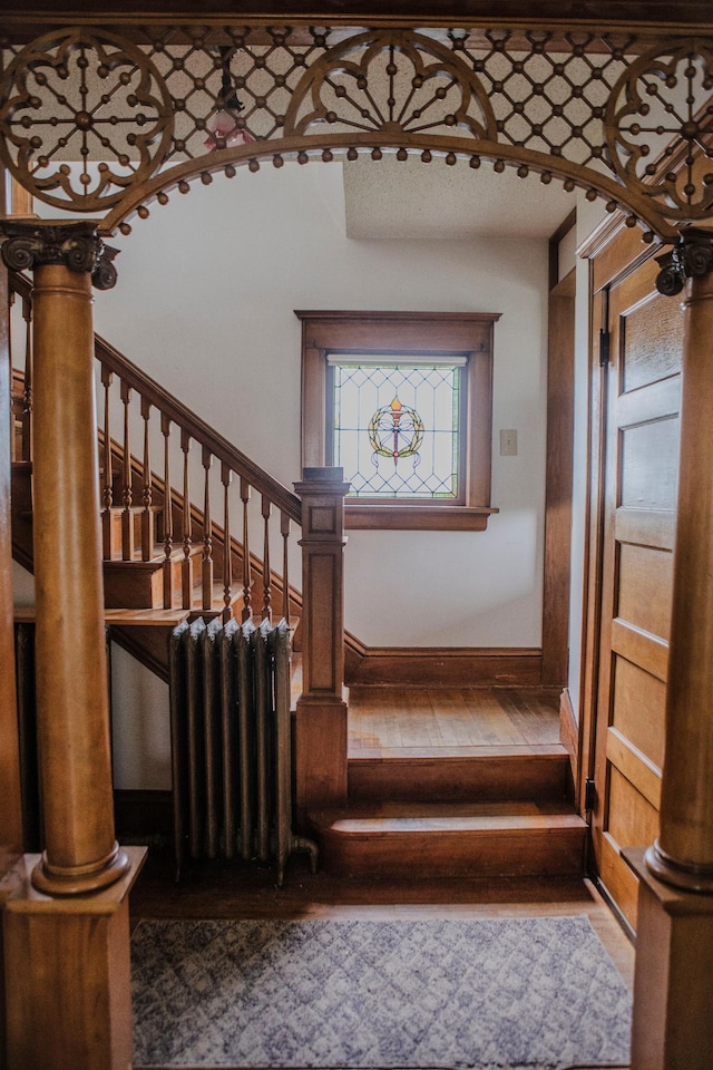 210 6th St, Morris, MN 56267 - stairs featuring radiator, hardwood / wood-style flooring, baseboards, and arched walkways