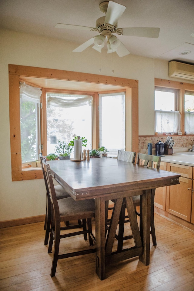 210 6th St, Morris, MN 56267 - dining area with a wall unit AC, light wood-style flooring, a ceiling fan, and baseboards