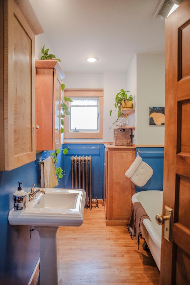 210 6th St, Morris, MN 56267 - full bath with radiator heating unit, a tub to relax in, wood finished floors, and recessed lighting