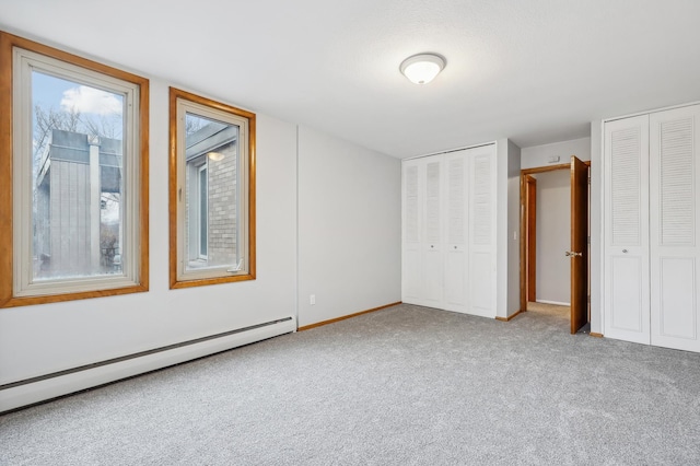 4029 14th Ave S Unit 14G, Minneapolis, MN 55407 - unfurnished bedroom with a baseboard heating unit, two closets, carpet, and baseboards