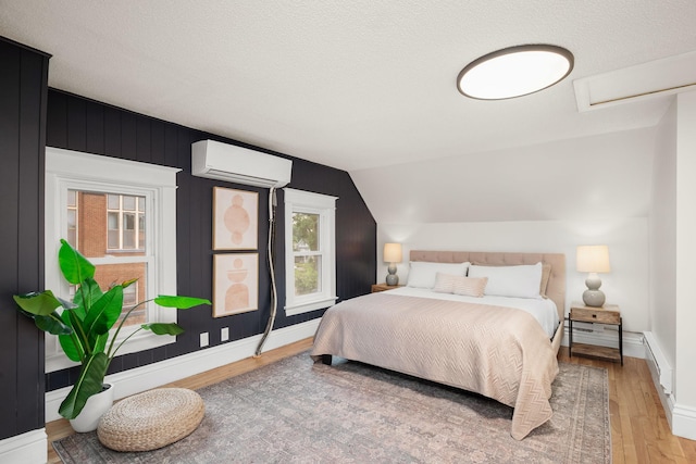 1836 Marshall Ave, Saint Paul, MN 55104 - bedroom featuring an AC wall unit, light wood finished floors, lofted ceiling, and a textured ceiling