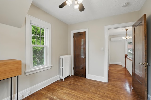 4848 Ewing Ave S, Minneapolis, MN 55410 - unfurnished bedroom with radiator, an AC wall unit, wood finished floors, and a chandelier
