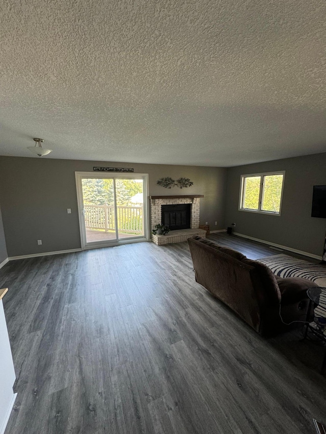4198 Hilltop Ln, Eagan, MN 55123 - unfurnished living room featuring a textured ceiling, dark wood-type flooring, a brick fireplace, and baseboards