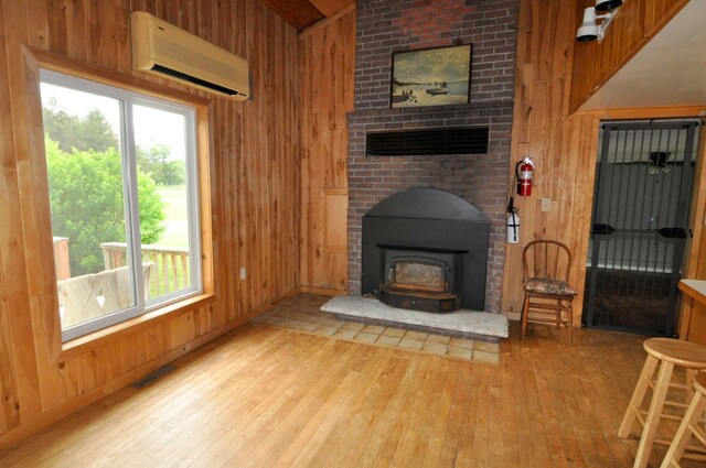 24892 277th Ave, Akeley Twp, MN 56467 - living room with a wall mounted air conditioner, wooden walls, wood-type flooring, and a wood stove