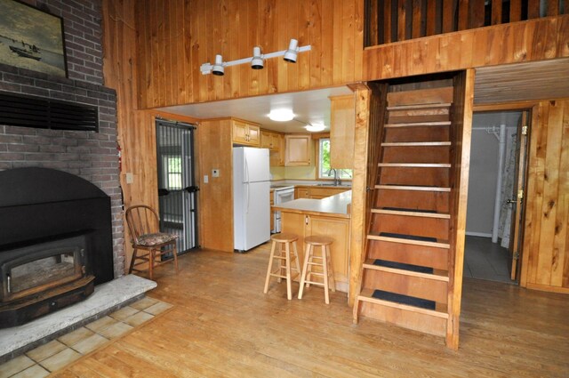24892 277th Ave, Akeley Twp, MN 56467 - kitchen with freestanding refrigerator, a towering ceiling, wood walls, light wood-style flooring, and a peninsula