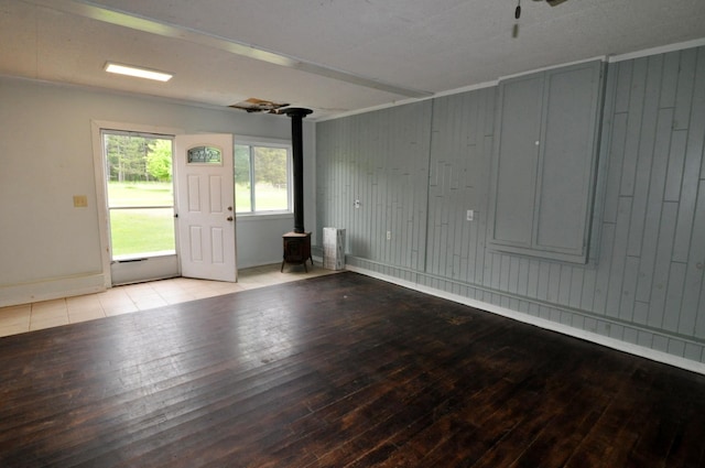 24892 277th Ave, Akeley Twp, MN 56467 - empty room featuring hardwood / wood-style floors, a wood stove, wood walls, and ceiling fan