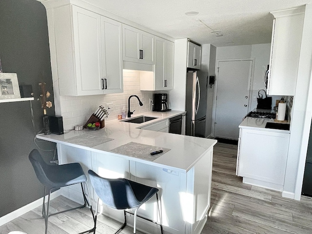 9106 Neill Lake Rd, Eden Prairie, MN 55347 - kitchen featuring stainless steel appliances, light wood-style flooring, decorative backsplash, light countertops, and a peninsula