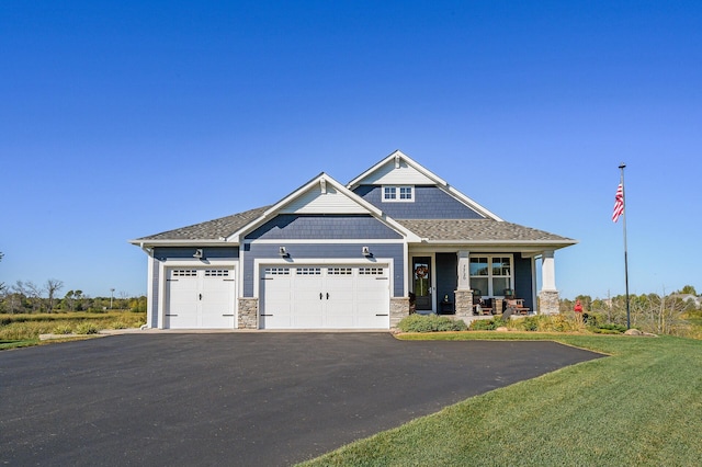 7720 242nd St, Wyoming, MN 55025 - view of front facade featuring driveway, a garage, covered porch, stone siding, and a front lawn