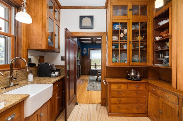 2525 2nd St, Duluth, MN 55812 - kitchen with a sink, ornamental molding, light wood finished floors, brown cabinets, and glass insert cabinets