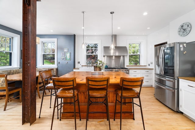 2525 2nd St, Duluth, MN 55812 - kitchen with smart refrigerator, wall chimney exhaust hood, wooden counters, light wood-style floors, and white cabinets