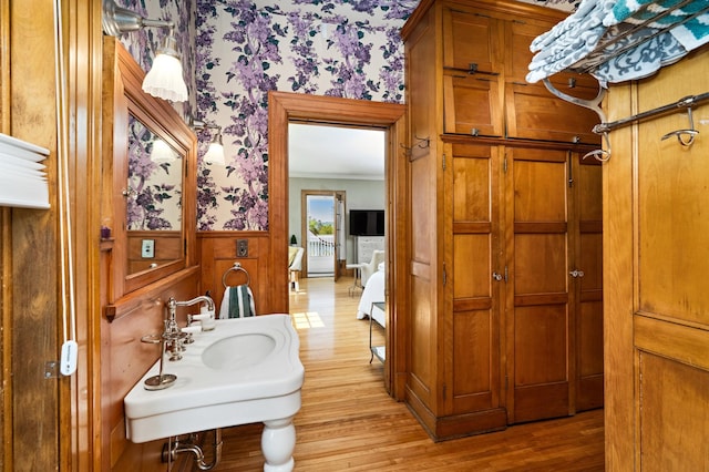 2525 2nd St, Duluth, MN 55812 - bathroom featuring wallpapered walls, wainscoting, wood finished floors, a sink, and crown molding