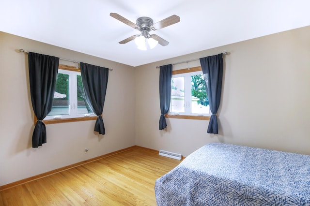 1821 4th Ave NE, Austin, MN 55912 - bedroom featuring multiple windows, baseboards, light wood-type flooring, and ceiling fan