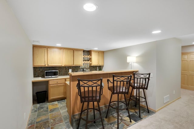 14925 Hillside Trl, Savage, MN 55378 - kitchen with stainless steel microwave, a breakfast bar area, recessed lighting, backsplash, and baseboards