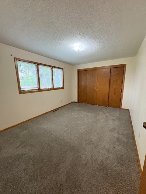 2220 23rd St NW, Rochester, MN 55901 - unfurnished bedroom with light colored carpet, a closet, a textured ceiling, and baseboards