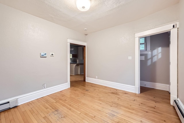 1156 Marion St, Saint Paul, MN 55117 - spare room with a baseboard radiator, light wood-style floors, baseboards, a textured ceiling, and baseboard heating