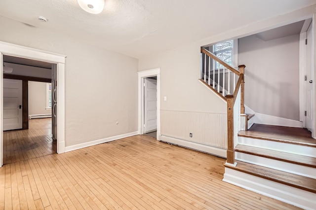1156 Marion St, Saint Paul, MN 55117 - unfurnished living room with hardwood / wood-style floors, baseboard heating, stairs, a baseboard heating unit, and a textured ceiling