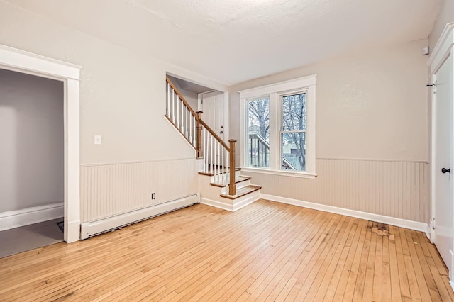 1156 Marion St, Saint Paul, MN 55117 - empty room with baseboard heating, wainscoting, wood-type flooring, and stairs