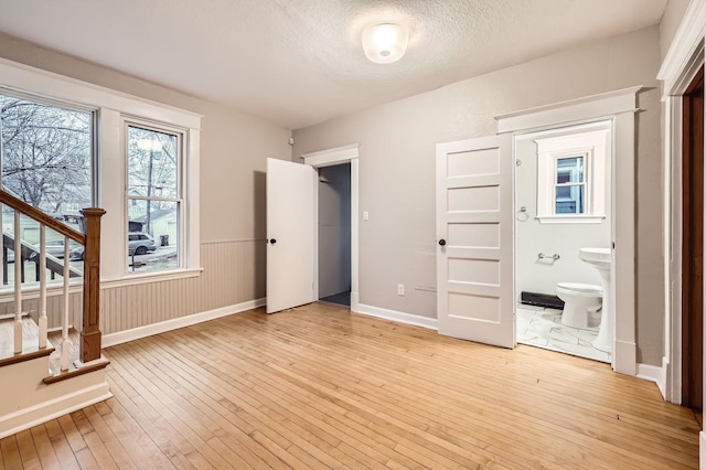 1156 Marion St, Saint Paul, MN 55117 - unfurnished bedroom with light wood-style flooring, a textured ceiling, baseboards, and ensuite bathroom