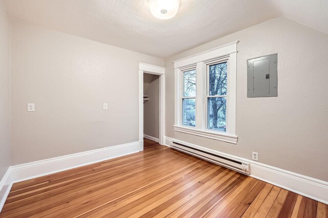 1156 Marion St, Saint Paul, MN 55117 - empty room with electric panel, a baseboard radiator, hardwood / wood-style floors, baseboards, and a textured ceiling
