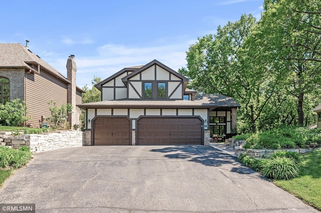 12143 Gantry Ln, Apple Valley, MN 55124 - tudor house with asphalt driveway, an attached garage, and stucco siding