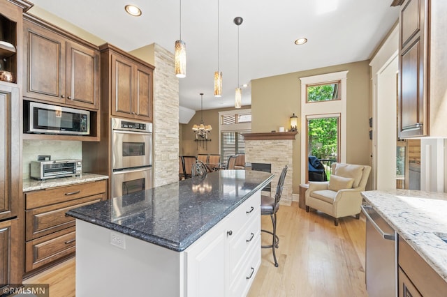12143 Gantry Ln, Apple Valley, MN 55124 - kitchen with stainless steel appliances, a breakfast bar area, light wood-style flooring, white cabinets, and a chandelier