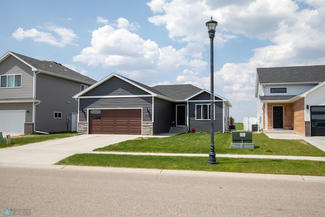 2700 14th St W, West Fargo, ND 58078 - view of front of house featuring driveway, an attached garage, a front lawn, and stone siding