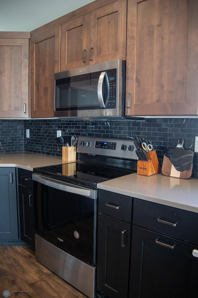2700 14th St W, West Fargo, ND 58078 - kitchen with appliances with stainless steel finishes, light countertops, dark wood-type flooring, and decorative backsplash