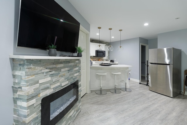 1712 Levee Ave, Anoka, MN 55303 - kitchen with freestanding refrigerator, black microwave, light wood-style flooring, a stone fireplace, and a peninsula