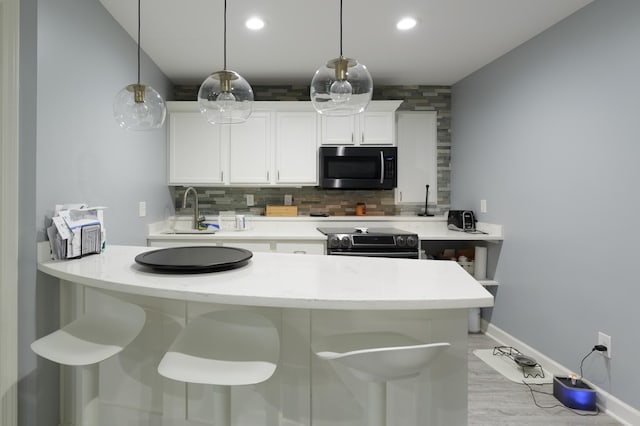 1712 Levee Ave, Anoka, MN 55303 - kitchen with stainless steel microwave, a sink, black range with electric cooktop, tasteful backsplash, and white cabinets
