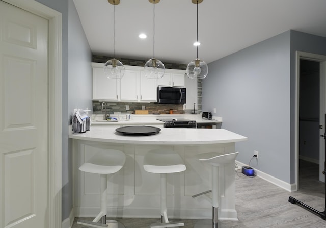 1712 Levee Ave, Anoka, MN 55303 - kitchen featuring tasteful backsplash, light countertops, electric stove, white cabinetry, and light wood finished floors