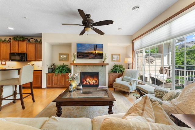 14518 Florissant Path Unit 3090, Apple Valley, MN 55124 - living room with light wood-style floors, a textured ceiling, a ceiling fan, and a fireplace