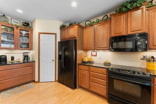 14518 Florissant Path Unit 3090, Apple Valley, MN 55124 - kitchen with black appliances, dark countertops, light wood finished floors, brown cabinetry, and glass insert cabinets