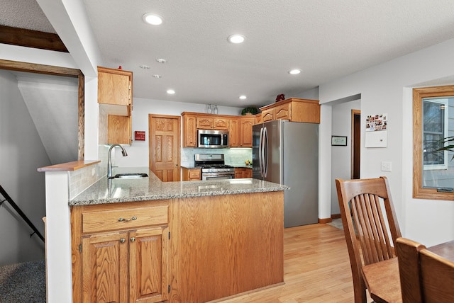 19260 81st Pl N, Maple Grove, MN 55311 - kitchen with stainless steel appliances, a sink, a peninsula, light wood-type flooring, and light stone counters