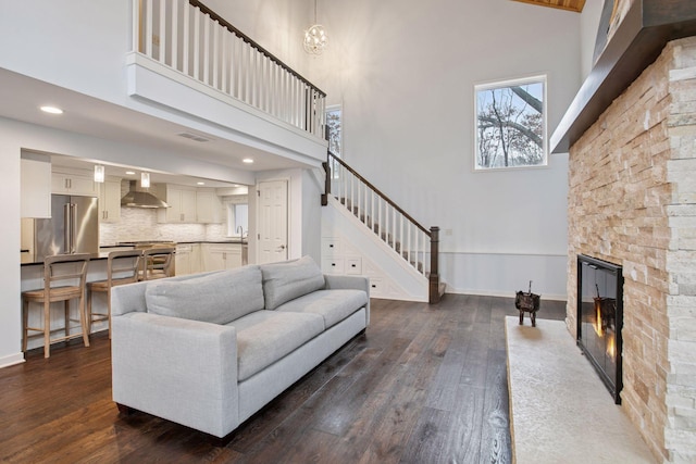 3715 Huntingdon Dr, Minnetonka, MN 55305 - living room featuring a towering ceiling, dark wood-style floors, a stone fireplace, stairs, and baseboards